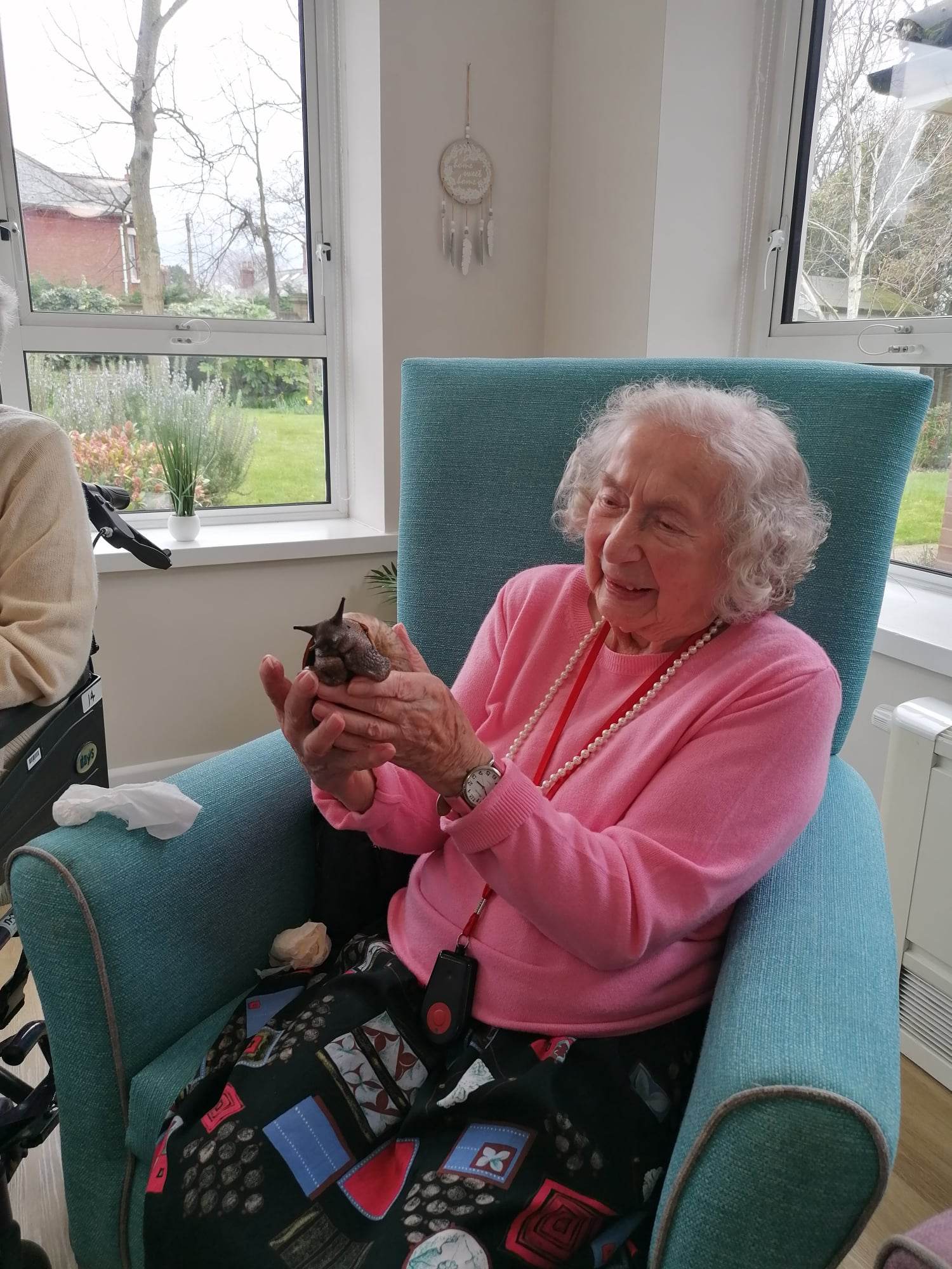 A resident wears smart clothing and smiles holding a giant land snail.