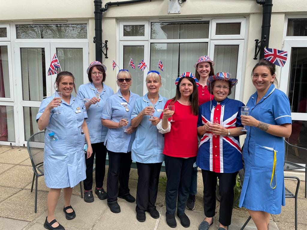 A group of Corton House staff dressed up for the Coronation, standing on a patio