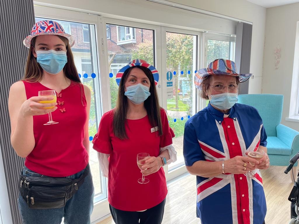 A volunteer, the Activities Assistant and the Chaplain celebrate the Coronation.