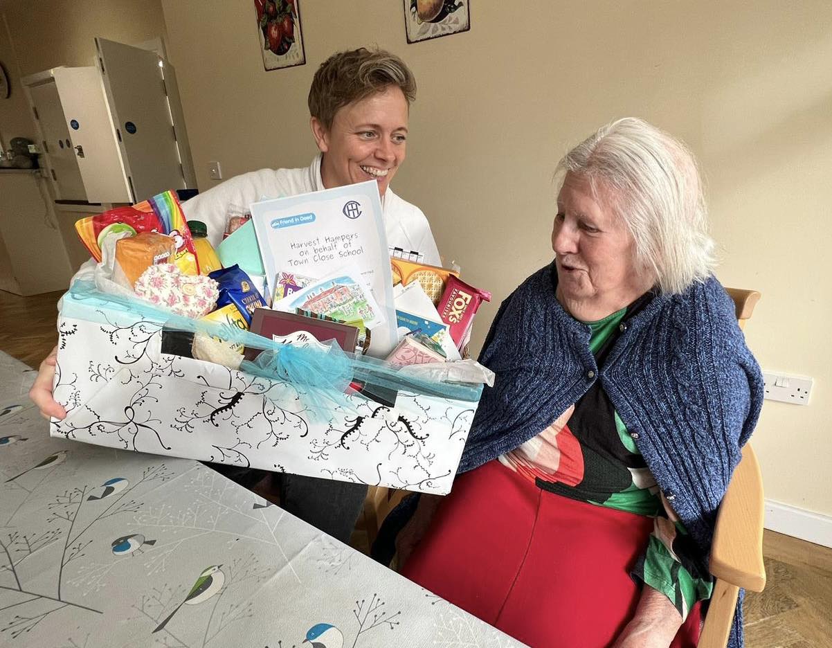 Friend in Deed founder Kelly shows resident Pam a hamper filled with treats.