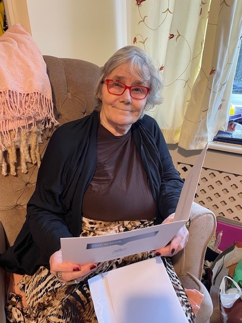 A Corton House resident opens a christmas card from norwich school pupils