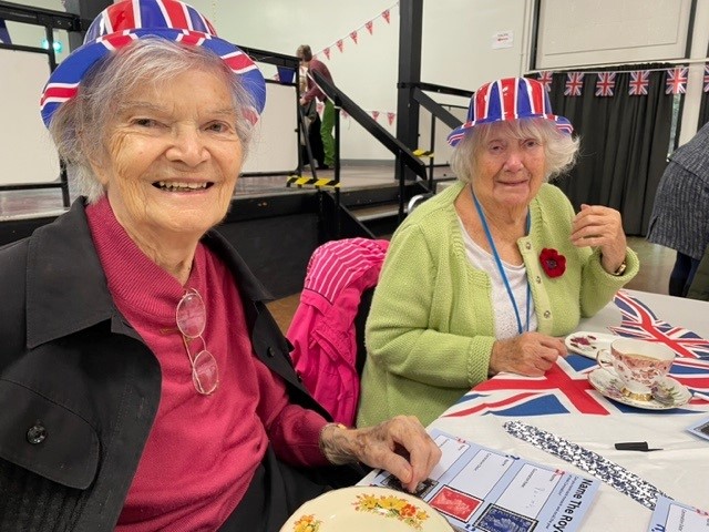 Two residents from Norwich care home Corton House smile wearing union jack hats