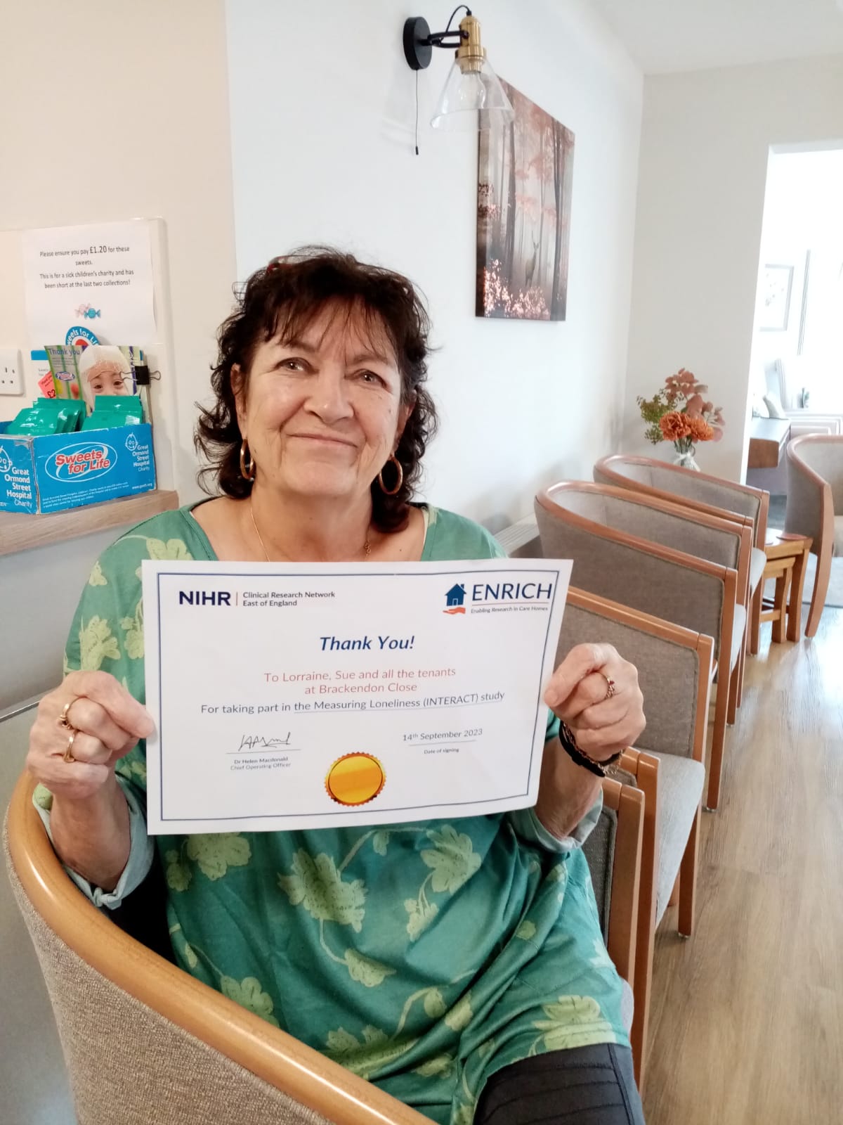 Scheme Manager Lorraine holds up a certificate of thanks from ENRICH