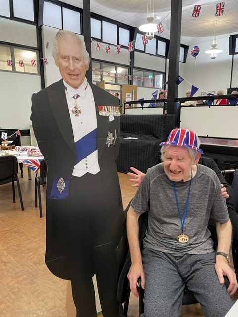Norfolk care home resident Martin smiles at the party, wearing a union flag hat