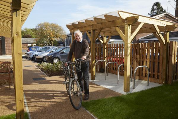 Independent Living Tenant smiles next to his bike and a purpose built bike shed.