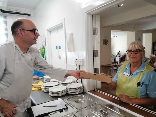 Corton House chef Sean hands a box of fish and chips to Care Assistant Jane