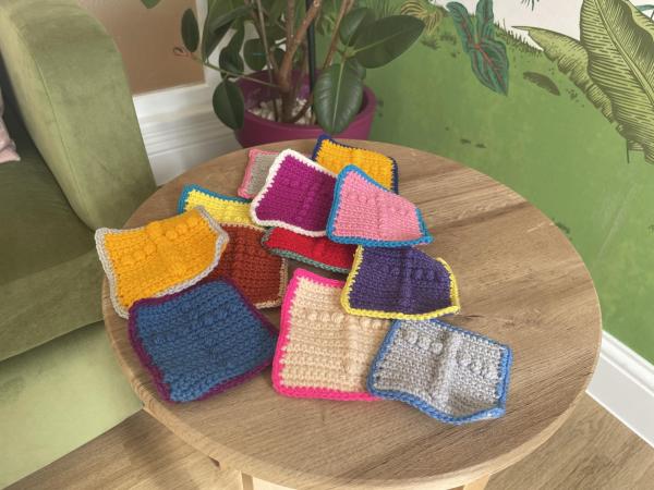 Bright knitted squares with tactile crosses in lots of colours.