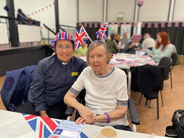 Corton House resident Delphine wears flags on her head with chaplain Rhonwen