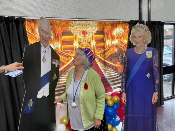Norwich care home resident Doreen smiles between cut outs of the king and queen