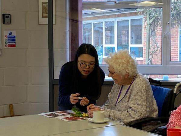 A volunteer and resident read a fortune cookie together.