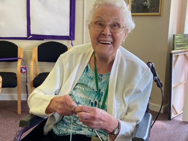 Happy resident laughing at Corton House while knitting