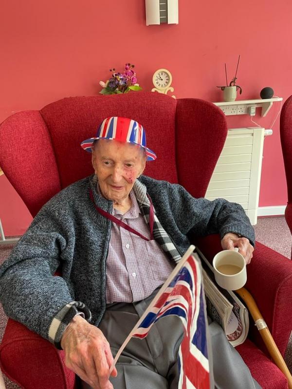 A Corton House resident smiles and waves a Union Jack flag