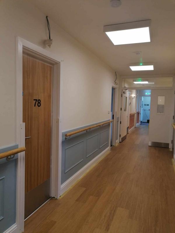 A corridor after refurbishment; it is brightly lit with panelling and oak floor
