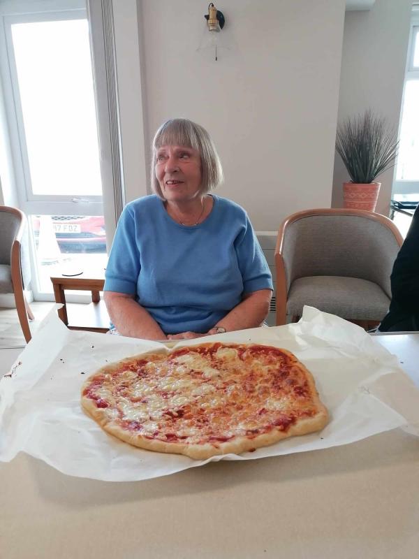 a happy Brakendon Close tenant sits with a pizza she has made.
