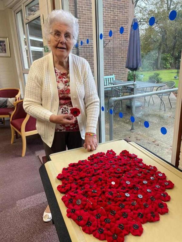 Corton House resident Norma smiles with a huge pile of hand knitted poppies