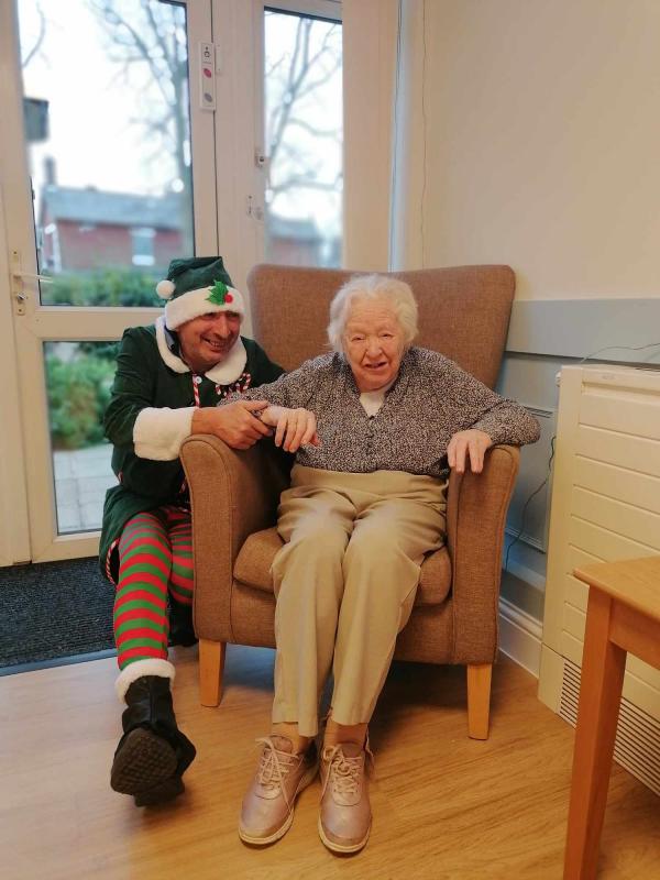A Corton House resident smiles next to a staff member dressed as an elf