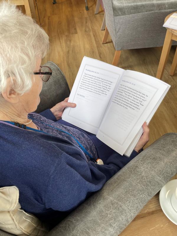 A resident reads the specially made worship service sheet at Corton House