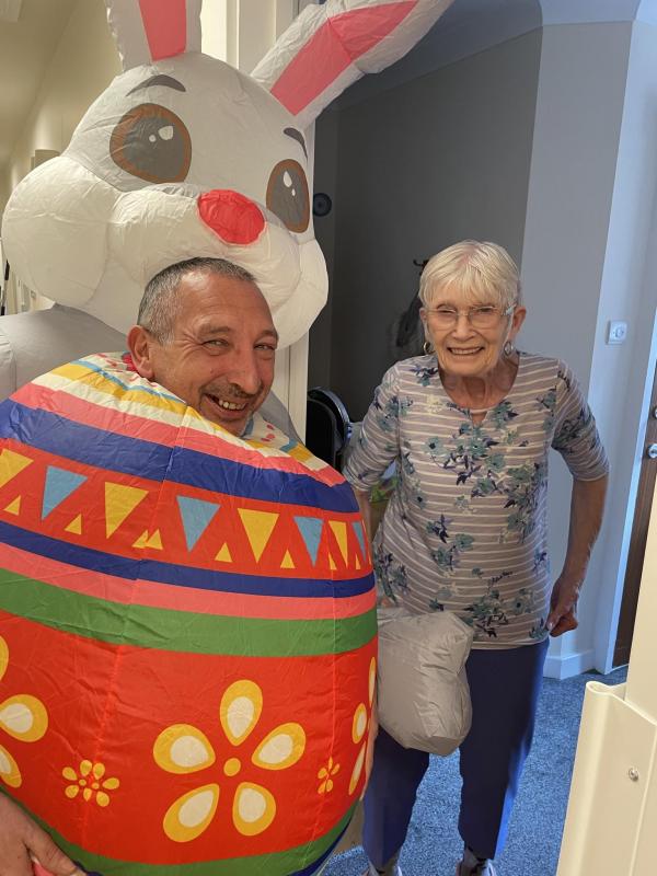 Smiling resident at Corton House in Norwich with staff dressed as Easter Bunny
