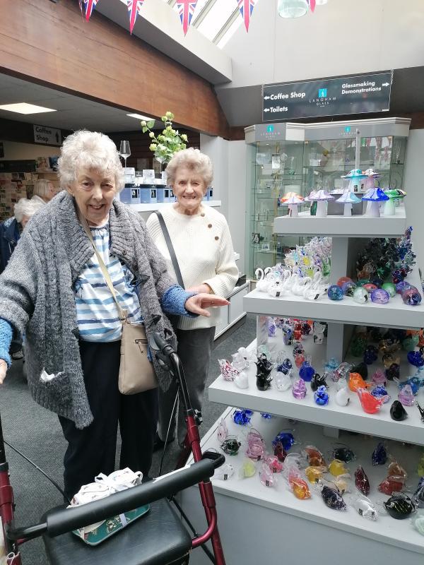Two smiling tenants from Brakendon Close in a gift shop surrounded by ornaments