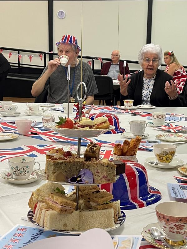 Afternoon tea on the table with smiling residents drinking tea at an event