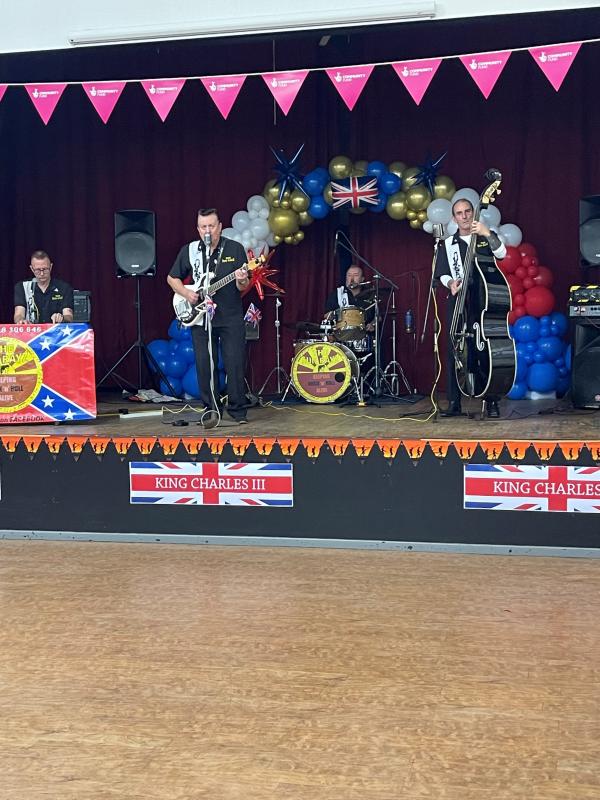 A band play onstage underneath union flag bunting