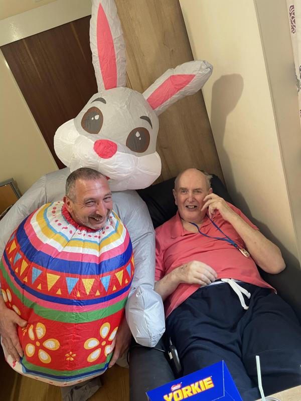 A care home resident smiles with the manager who is dressed at the Easter bunny