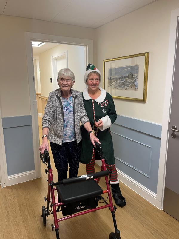A resident smiles with a staff member dressed as an elf.