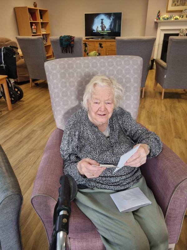 Resident Joyce smiles with a Christmas card in Corton House Care Home, Norwich