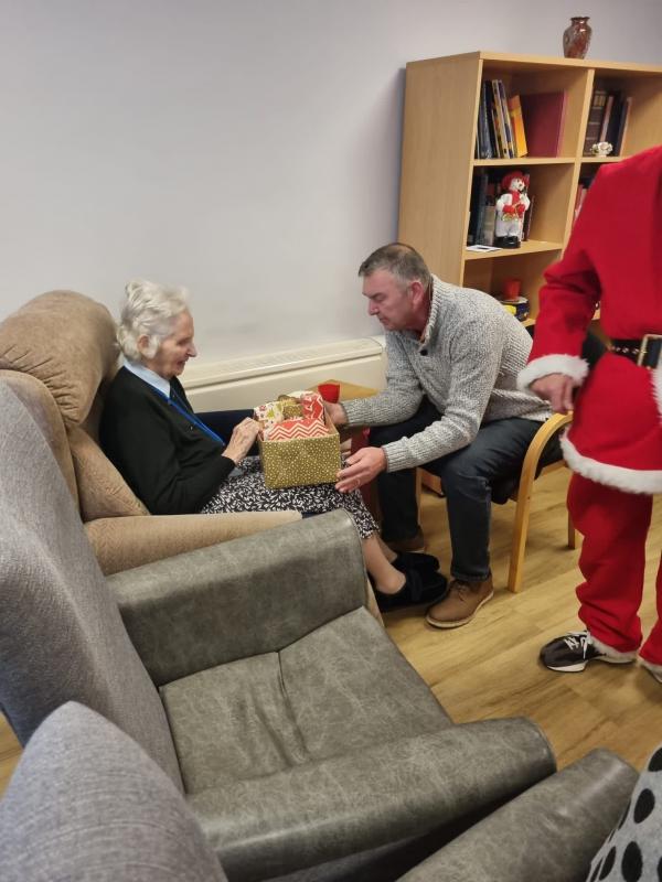 A resident and visitor open a box of gifts together at Christmas in Corton House