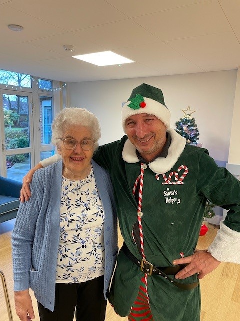 Manager Jason dressed as an elf, hugging a smiling care home resident.