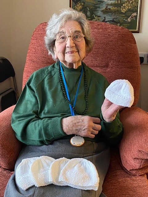 Care home resident Elsie smiles with hats knitted for local hospital in Norwich