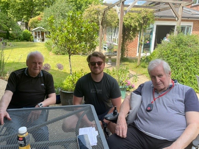 Resident Geoff sits at a garden table with his family