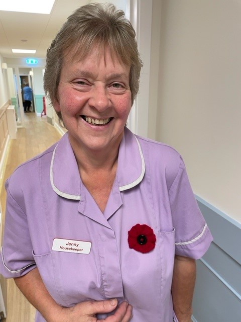 A smiling member of the housekeeping team at Corton House wears a poppy