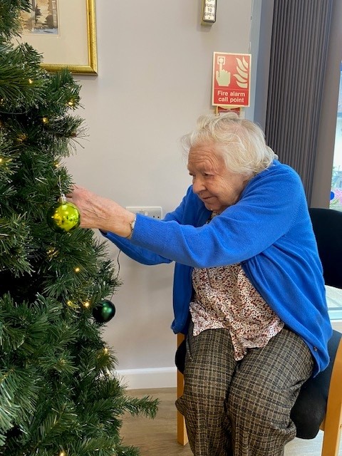 A resident hangs a bauble on the tree at Norfolk care home Corton House