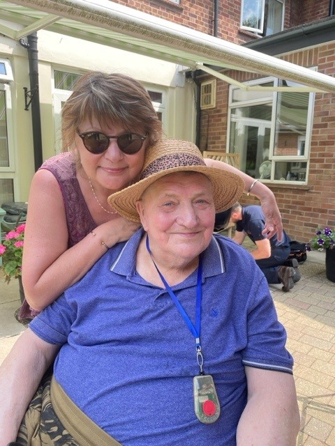 Resident Ken with his daughter smiling on the patio.