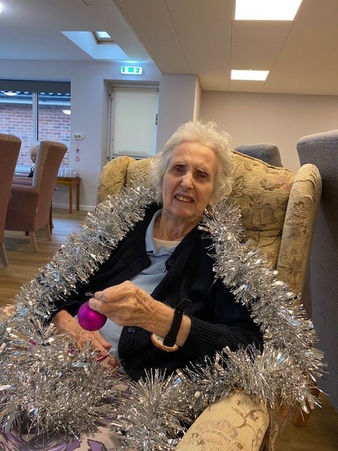 A resident wrapped in tinsel decorating the tree at Norwich care home Corton