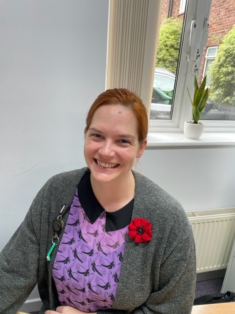 Norwich residential care home administrator Sophie smiles and wears a poppy