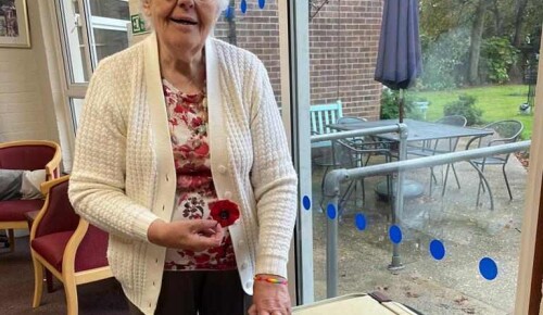 Norwich care home resident Norma with a pile of knitted poppy brooches sold to raise money for charity.