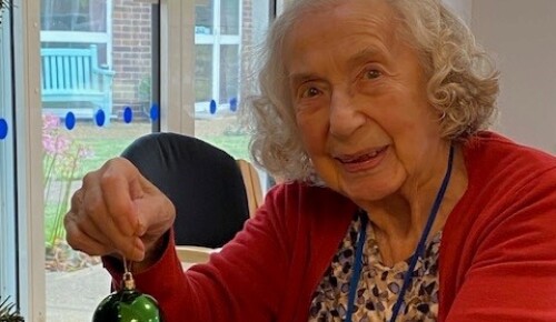 Resident Audrey hangs a bauble on the tree at Norwich Care Home Corton House